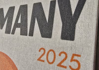 Text 'GERMANY 2025' on a textured surface with a colorful design.