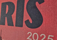 Text 'PARIS 2025' on a red background with a blurred image of the Eiffel Tower.