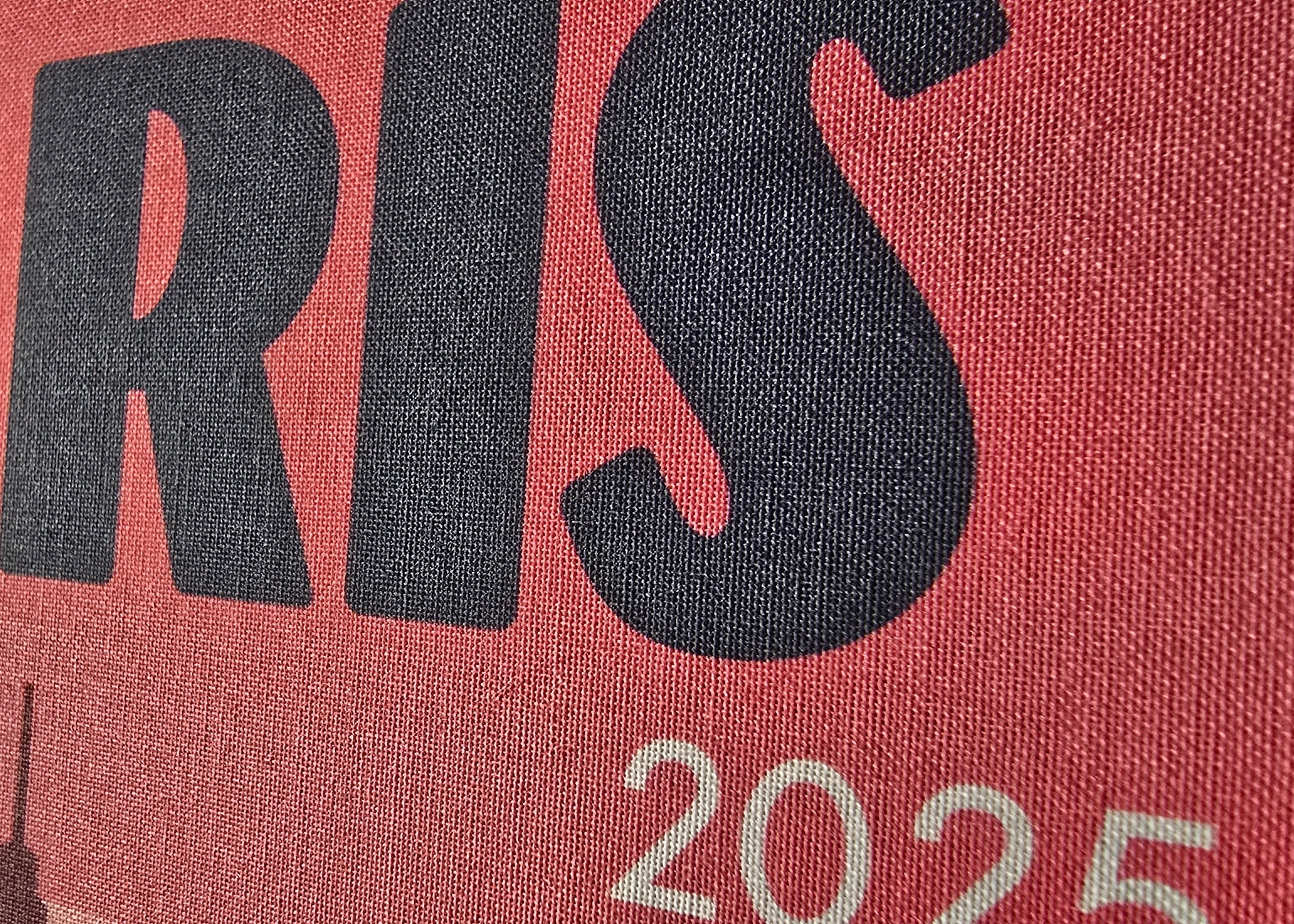 Text 'PARIS 2025' on a red background with a blurred image of the Eiffel Tower.