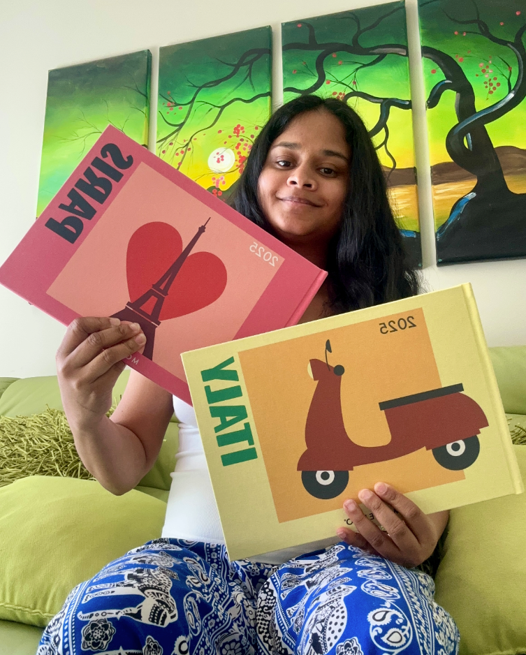 Person holding two books with artistic covers in front of colorful wall art